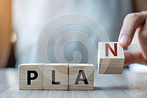 Businesswoman hand holding wooden cube with PLAN text on table background. Goals, success, strategy, solution and business