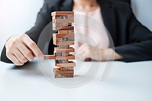 Businesswoman hand placing or pulling wooden block on the tower. Business planning, Risk Management, Solution and strategy