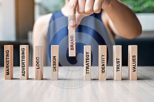 Businesswoman hand placing or pulling wooden Dominoes with BRAND text. and Marketing, Advertising, Logo, Design, Strategy,
