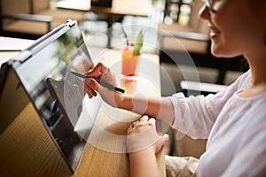 Businesswoman hand pointing with stylus on the chart over convertible laptop screen in tent mode. Woman using 2 in 1