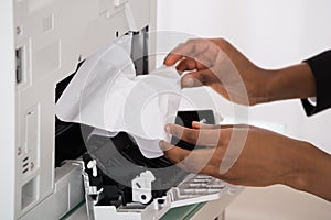 Businesswoman Hand Removing Paper Stucked In Printer