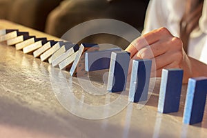 Businesswoman hand trying to stop toppling dominoes on table photo