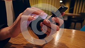 Businesswoman hands texting, sending sms on smartphone and drinking coffee in cafe. 4k, slow motion.