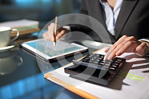 Businesswoman hands using tablet and calculator in the night