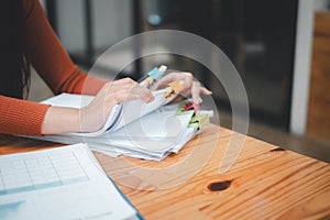 Businesswoman hands working in Stacks of paper files for searching and checking unfinished document achieves