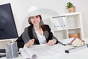 Businesswoman In Hardhat With Blueprints