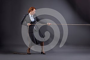 Businesswoman hauling at a rope