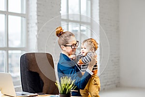 Businesswoman having fun with her baby son at the office
