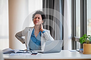 Businesswoman having neck pain and backache due to office workload