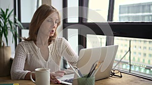 Businesswoman having online talk in front of laptop screen and sitting at table in home office.