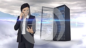 Businesswoman having phone call and holding tablet computer in front of server tower