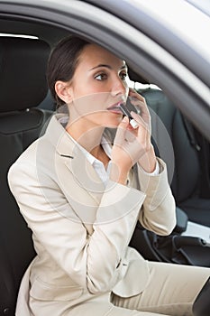 Businesswoman having a phone call while putting on lipstick