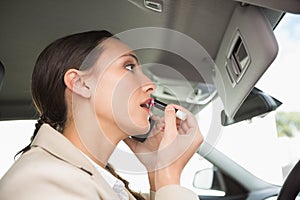 Businesswoman having a phone call while putting on lipstick