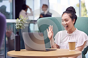 Businesswoman Having Video Call On Laptop At Table In Breakout Seating Area Of Office Building 