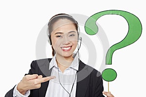 Businesswoman with headset holding up a question mark symbol