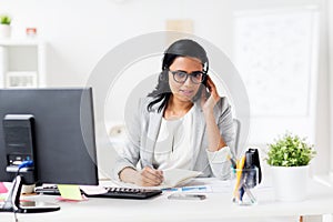 Businesswoman with headset and notebook at office