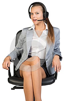 Businesswoman in headset sitting on office chair