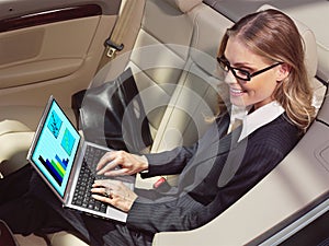 Businesswoman in her car with laptop