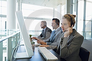 Businesswoman with her colleagues talking on headset at desk