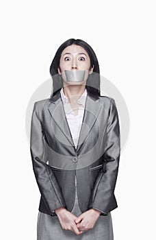 Businesswoman with her mouth caver with duct tape, studio shot