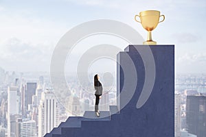 A businesswoman on her pathway to success, ascending stairs towards a trophy against a cityscape backdrop