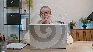Businesswoman hiding behind laptop computer, making funny face fooling around putting his tongue out