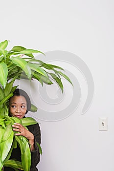 Businesswoman hiding behind office plant