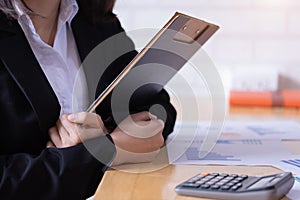 Businesswoman hold in arms with paper clipped pad at office workplace