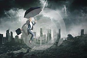 Businesswoman hold umbrella on storm background