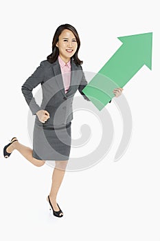 Businesswoman holding an arrow, pointing upwards