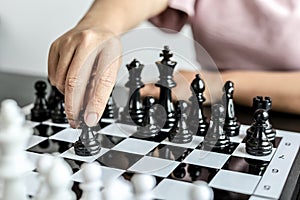 A businesswoman holding a black chess piece walks forward on a chessboard, comparing the chessboard to business administration.