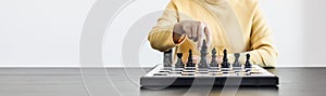 A businesswoman holding a black chess piece walks forward on a chessboard, comparing the chessboard to business administration.