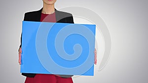 Businesswoman holding blank whiteboard sign on gradient background.