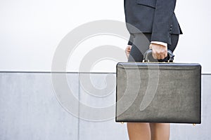 Businesswoman holding briefcase outdoors