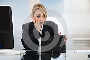 Businesswoman holding broken digital tablet
