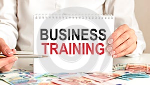 Businesswoman holding a card with text BUSINESS TRAINING