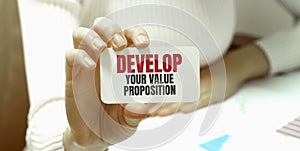 Businesswoman holding a card with text Develop Your Value Proposition
