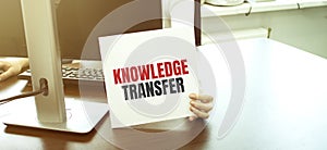 Businesswoman holding a card with text KNOWLEDGE TRANSFER