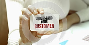 Businesswoman holding a card with text UNDERSTAND YOUR CUSTOMER