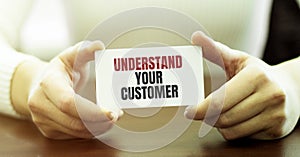 Businesswoman holding a card with text UNDERSTAND YOUR CUSTOMER