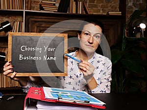 BusinessWoman holding a chalkboard. Business concept about Choosing Your Business Name with phrase on the sheet