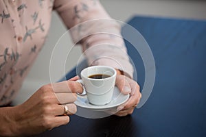 Businesswoman holding coffee cup and saucer in cafe