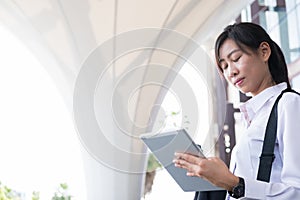 Businesswoman holding coffee and digital tablet outside office b
