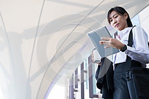 Businesswoman holding coffee and digital tablet outside office b