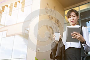 Businesswoman holding coffee and digital tablet outside office b