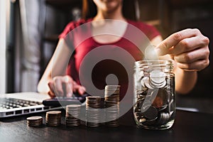 Businesswoman holding coins putting in glass with using smartphone and calculator to calculate  concept saving money