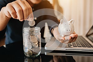 Businesswoman holding coins putting in glass with using smartphone and calculator to calculate  concept saving money into piggy