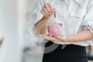 Businesswoman holding coins putting into piggy for saving money wealth and financial concept.