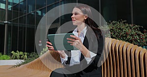 Businesswoman holding digital tablet device on city street glass background. Woman using tablet computer near office