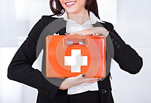Businesswoman holding first aid box